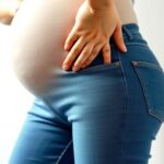 Pelvic Pain in Pregnancy: When to Seek Help Pregnant person indicating pelvic discomfort related to symphysis pubis dysfunction